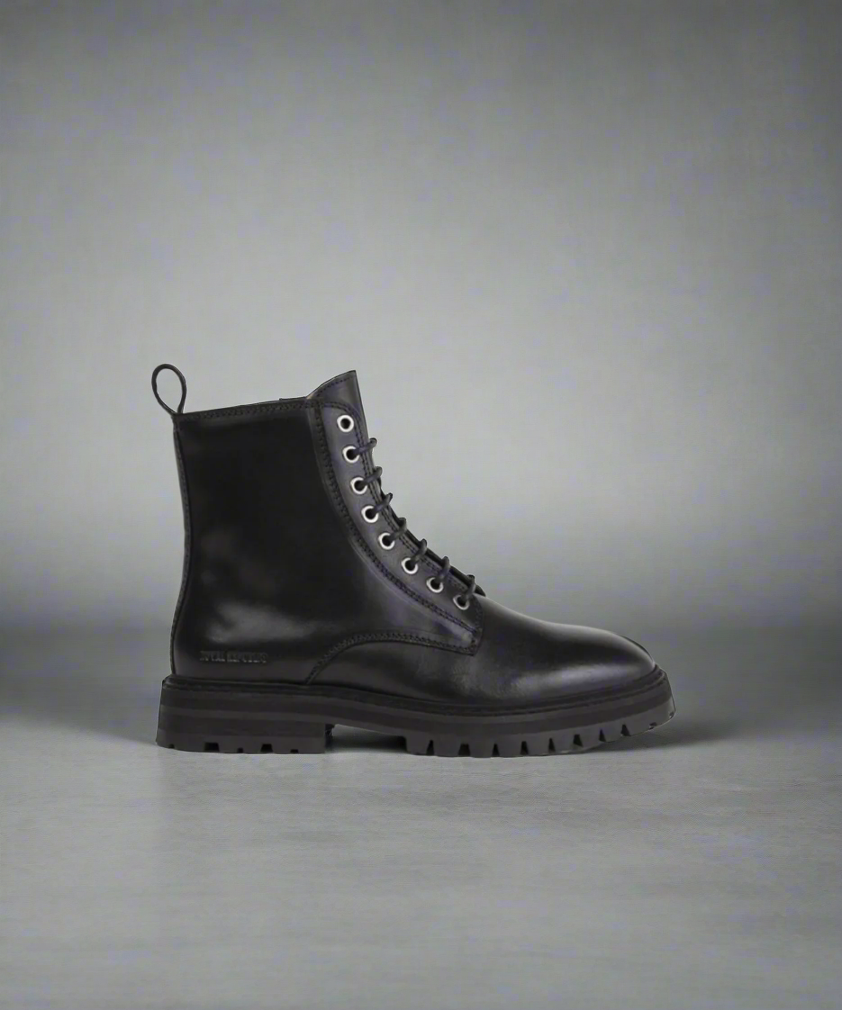 Black leather boot on a gray background