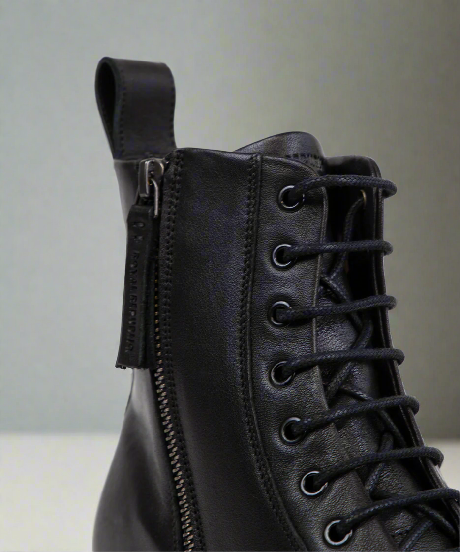 Black leather boot with a zipper on a neutral background