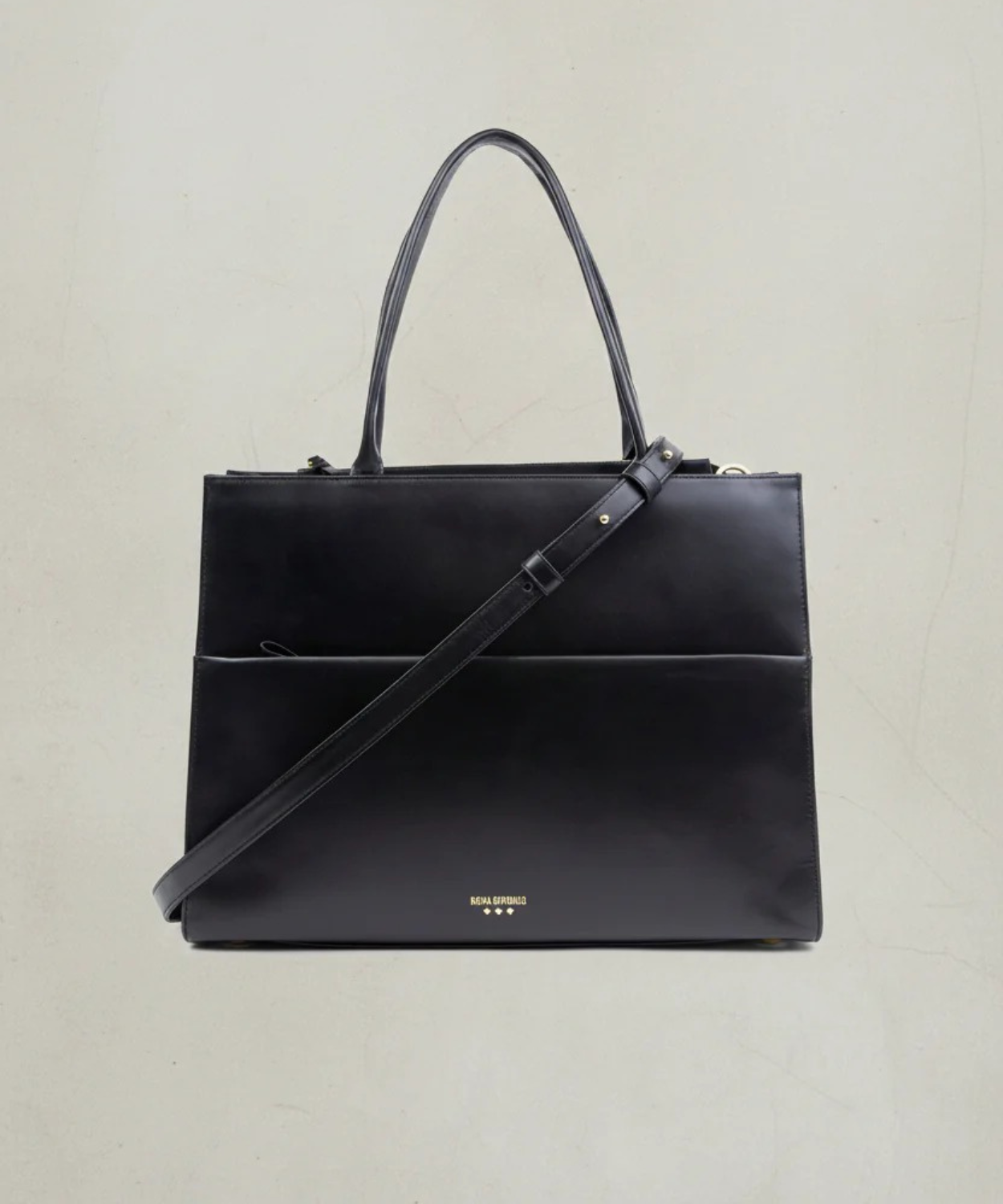 Black handbag with a shoulder strap on a light beige background