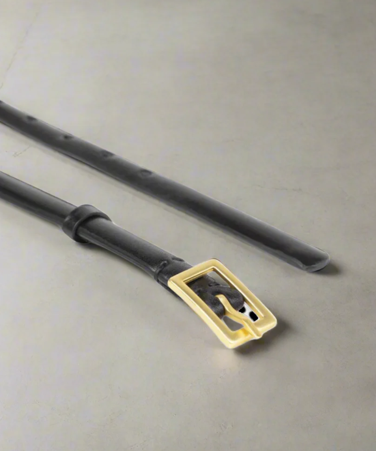 Black Royal RepubliQ Women's leather belt with a gold buckle on a gray background