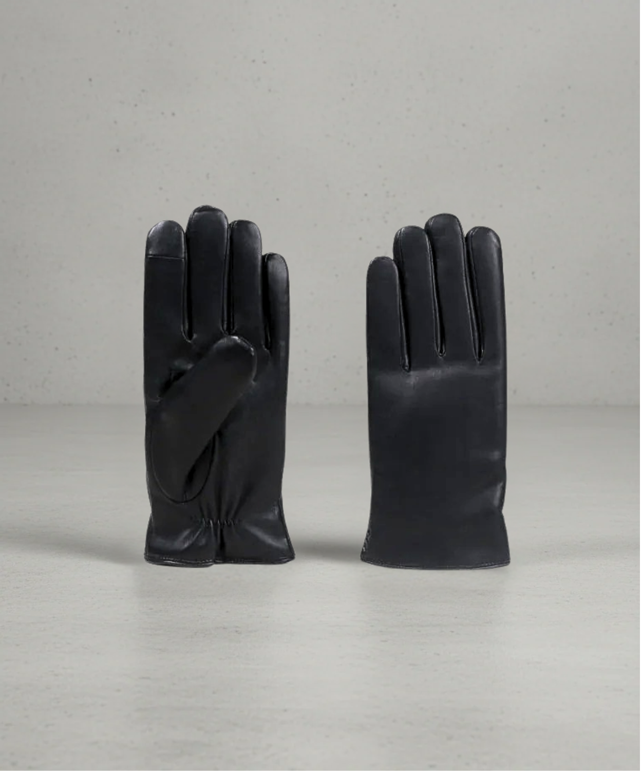 Pair of black leather gloves on a light gray background