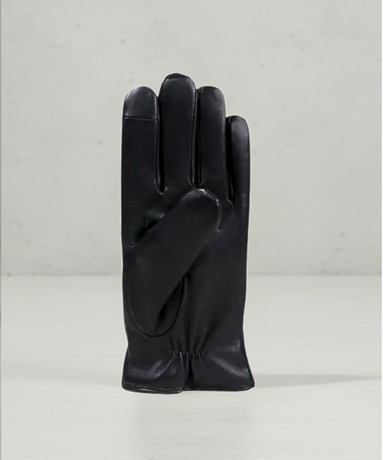 Black leather glove on a light gray background