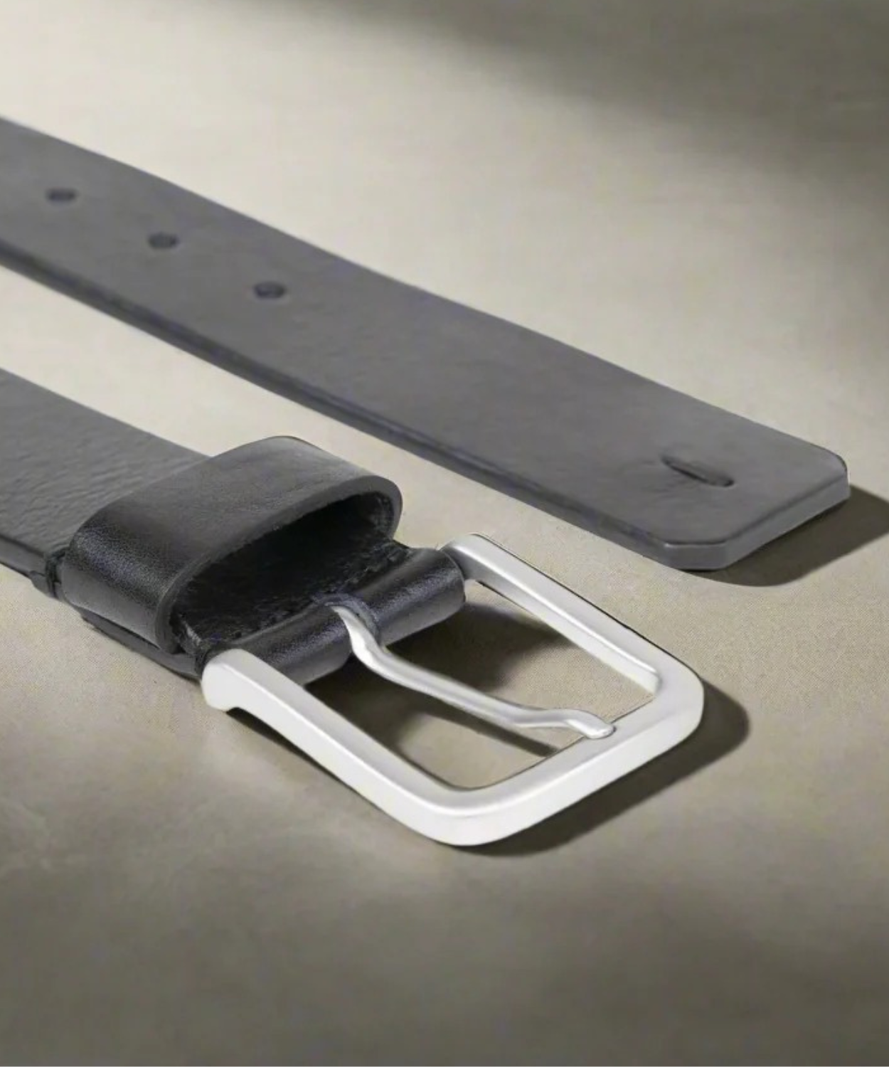 Black Royal RepubliQ leather belt with a matt silver buckle on a gray surface