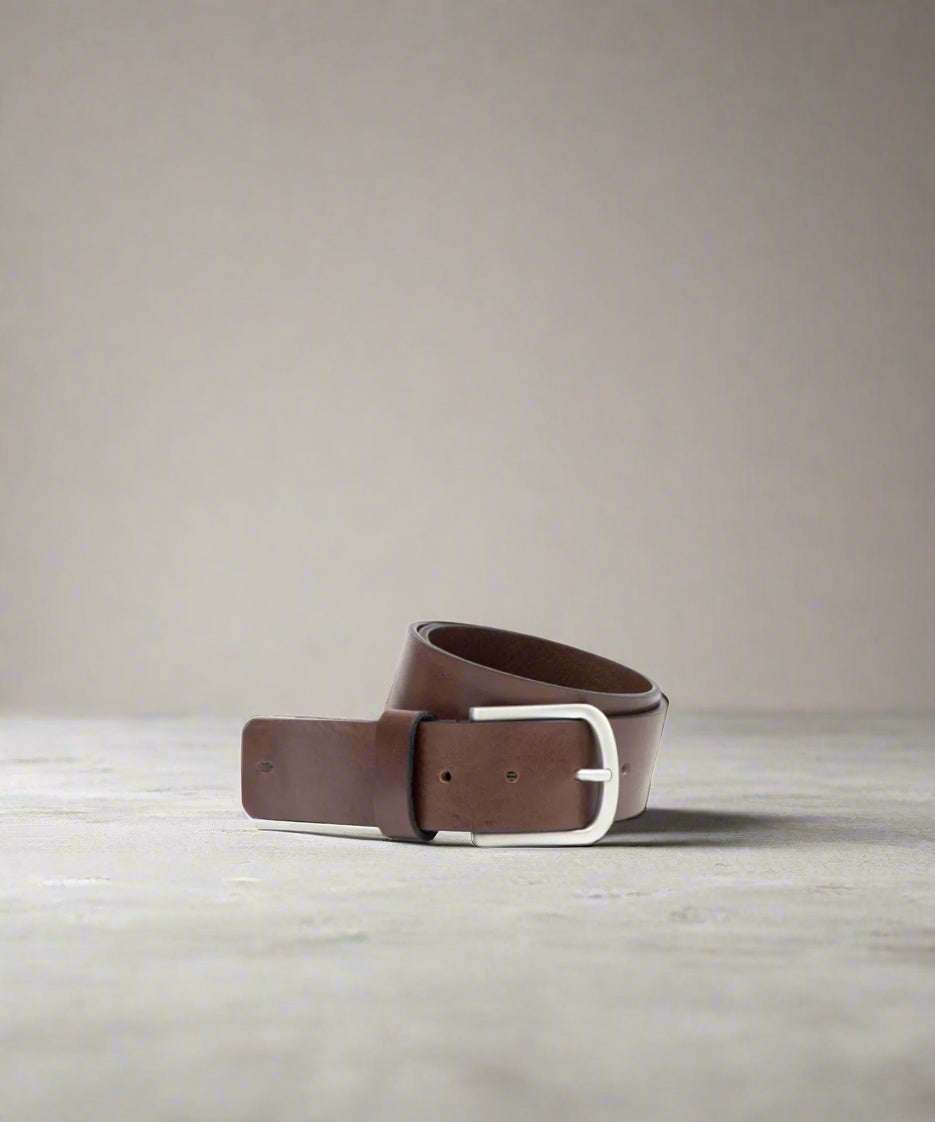 Brown Royal RepubliQ leather belt with a silver buckle on a beige background