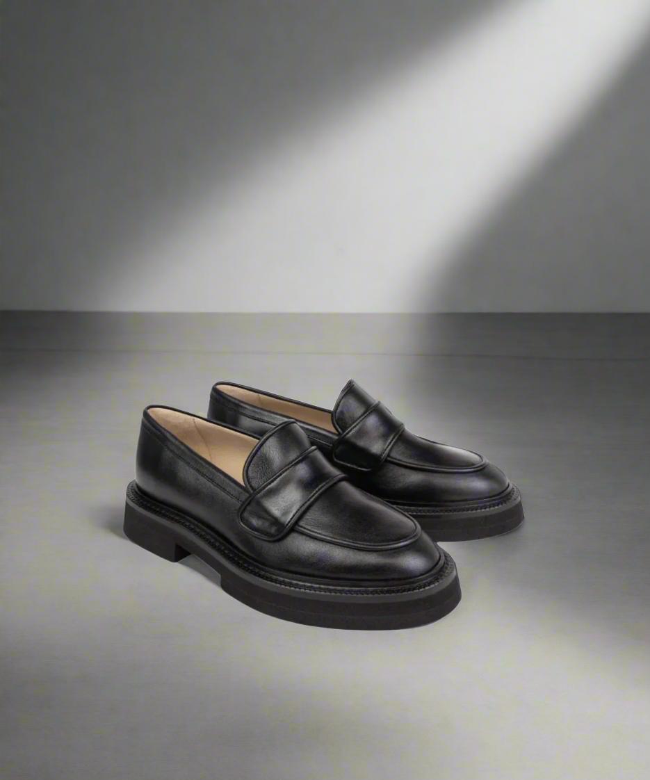 Pair of black loafers on a gray background