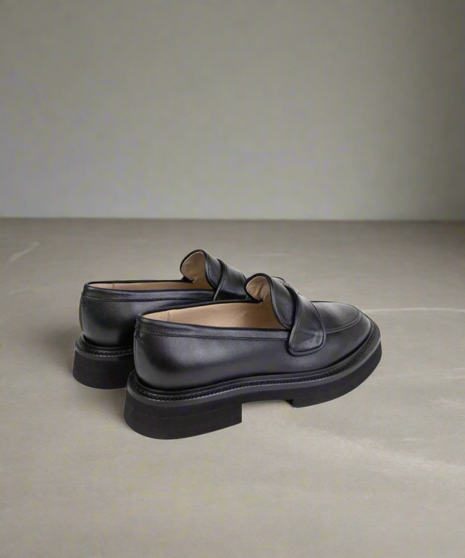 Pair of black loafers on a neutral background
