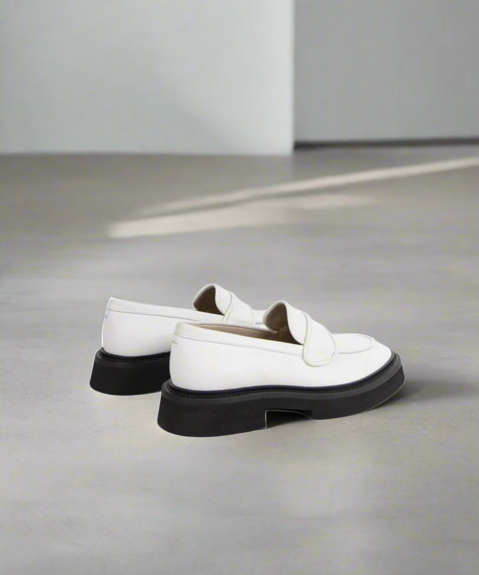 White loafers with black soles on a gray background