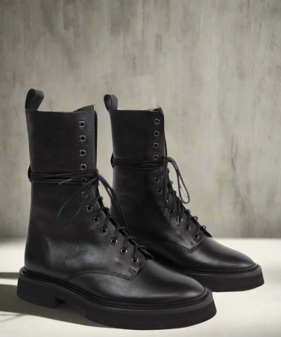 Pair of black leather boots on a neutral background