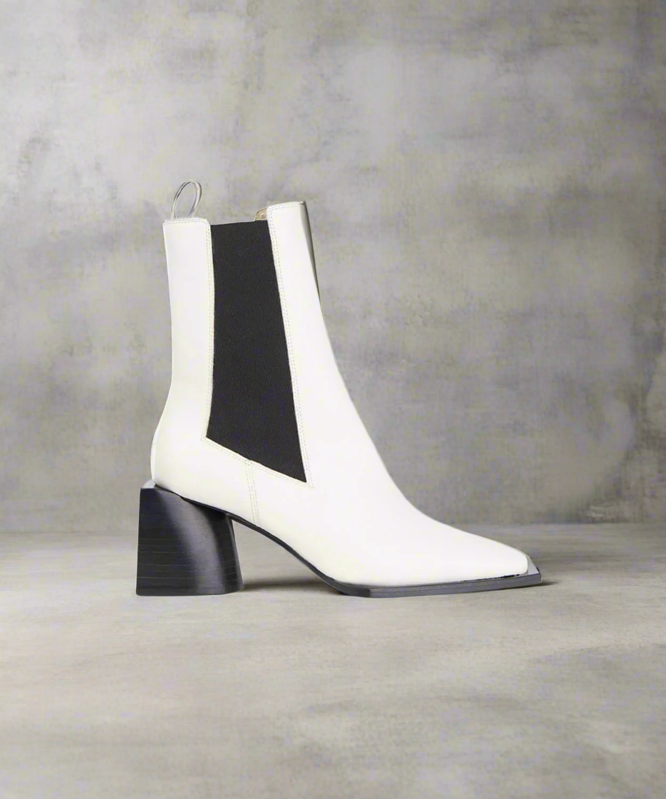 White ankle boot with black heel and side panel on a gray background