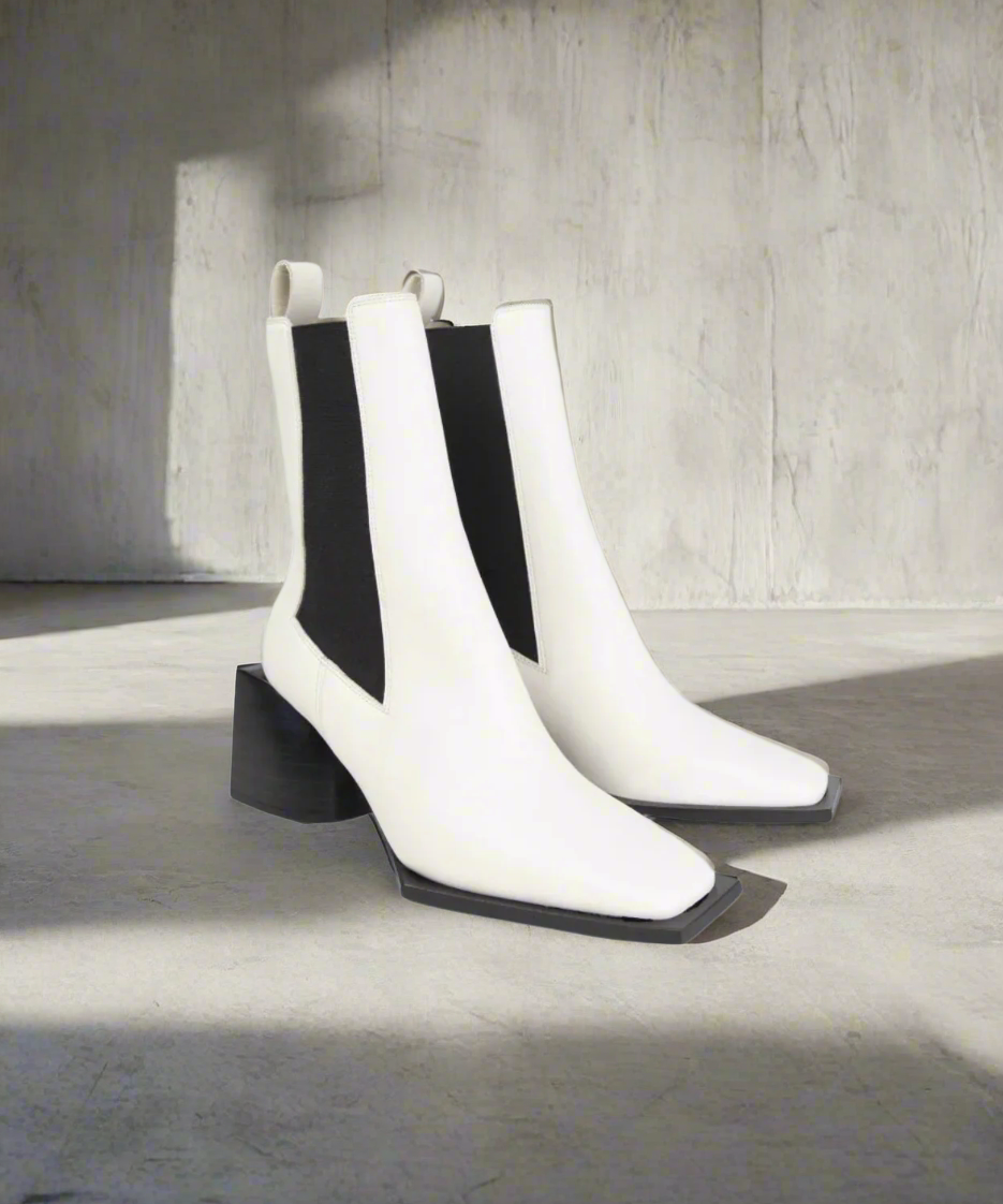Pair of white and black ankle boots on a gray background