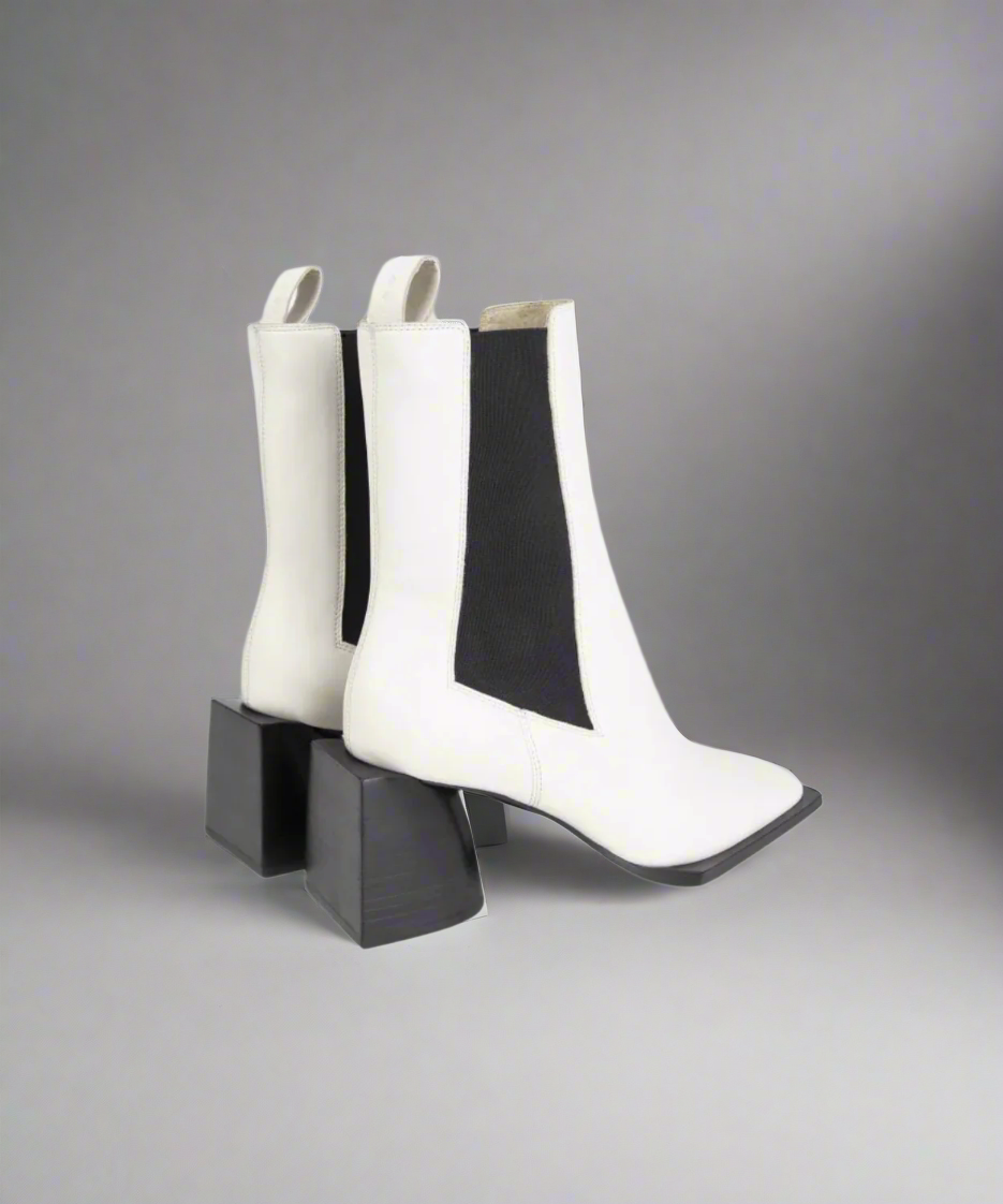 White ankle boots with black block heels on a gray background