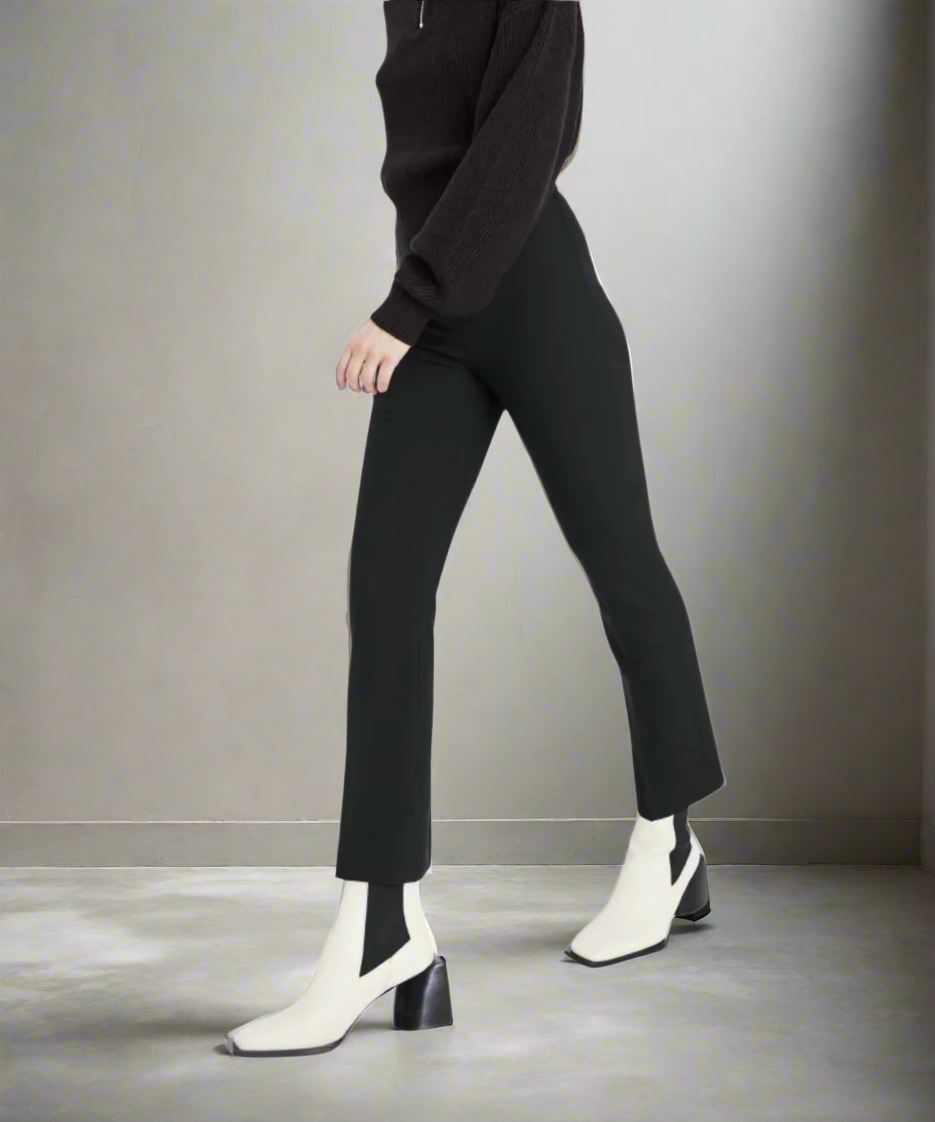 Person wearing black pants and white boots on a gray background