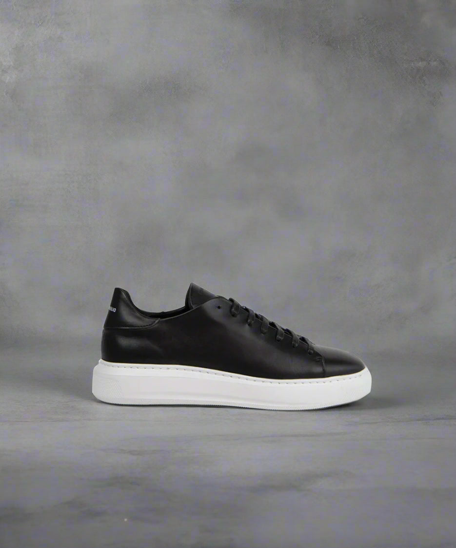 A black low-top sneaker with a white sole, lace-up closure, and subtle embossed details.