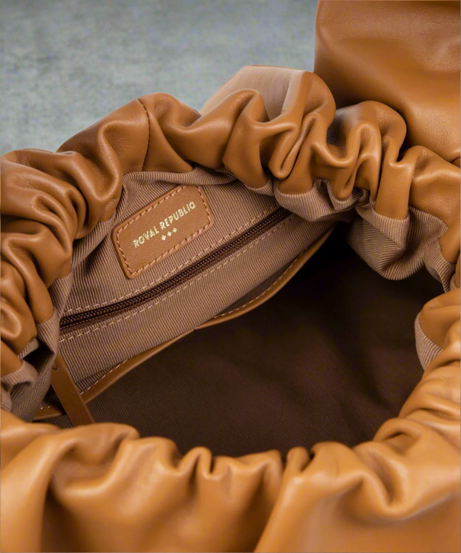Close-up of a brown tan leather bag with a visible brand logo.