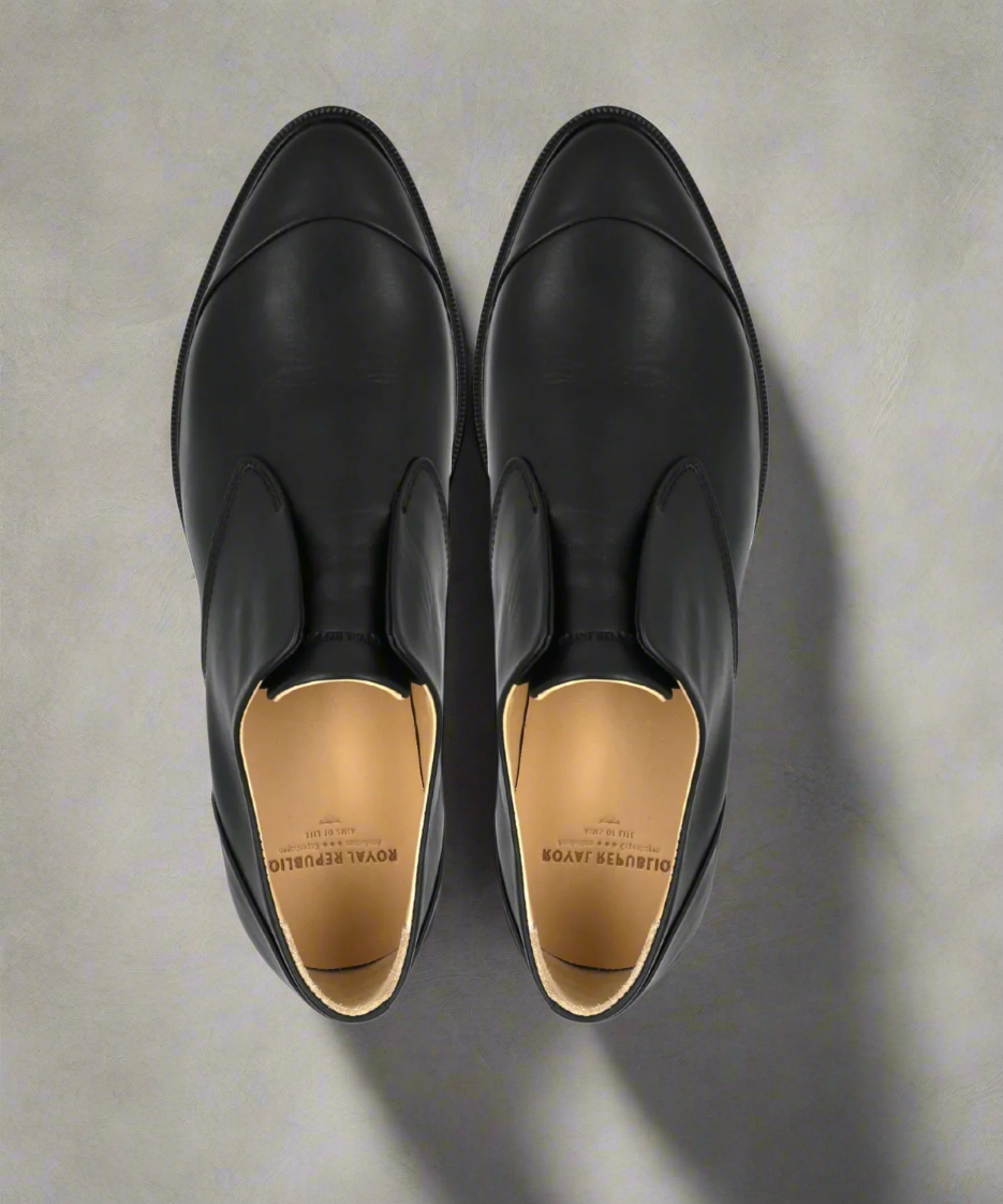 Pair of black Royal RepubliQ leather shoes on a white background