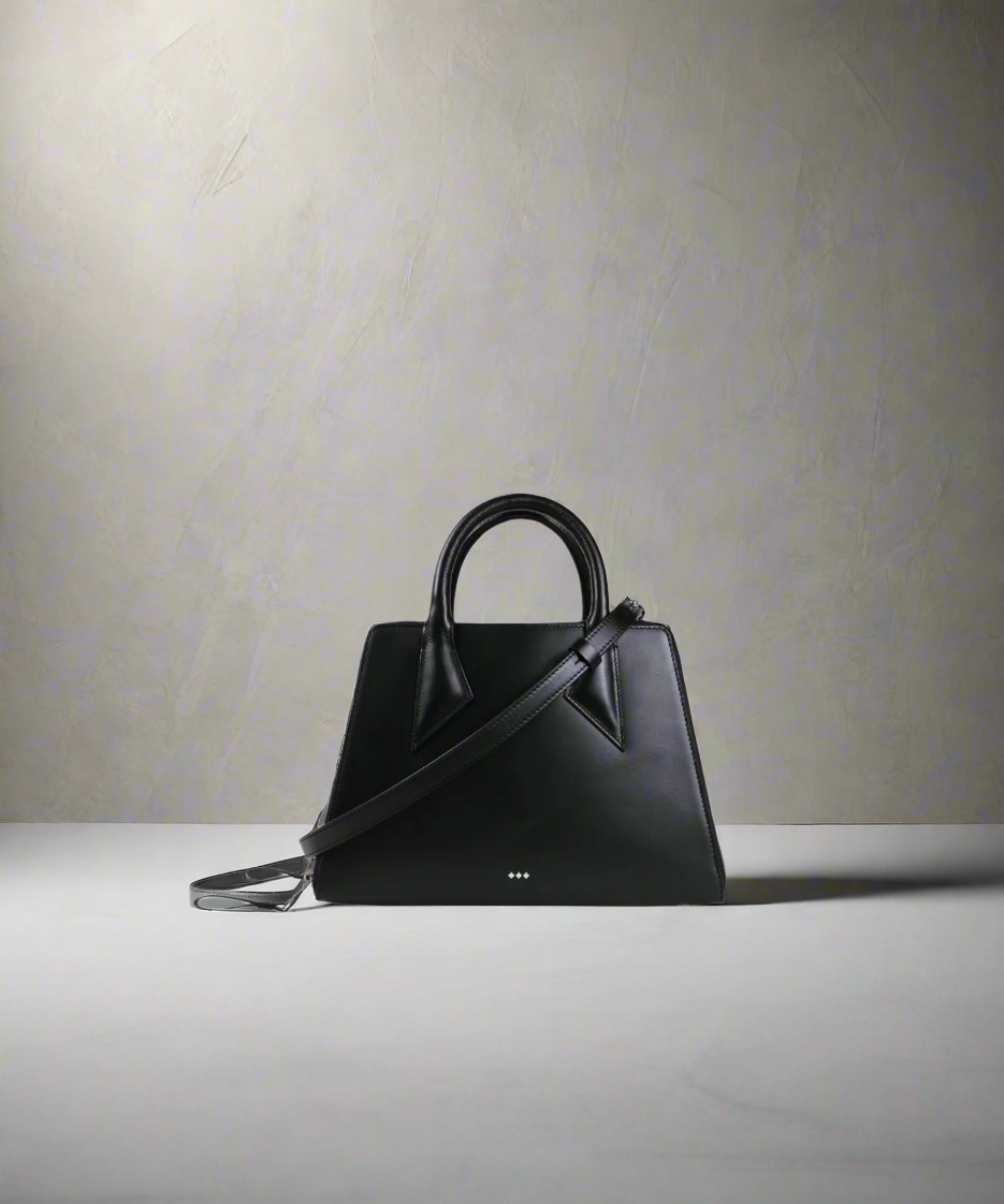 Black handbag on a light gray surface with a neutral background
