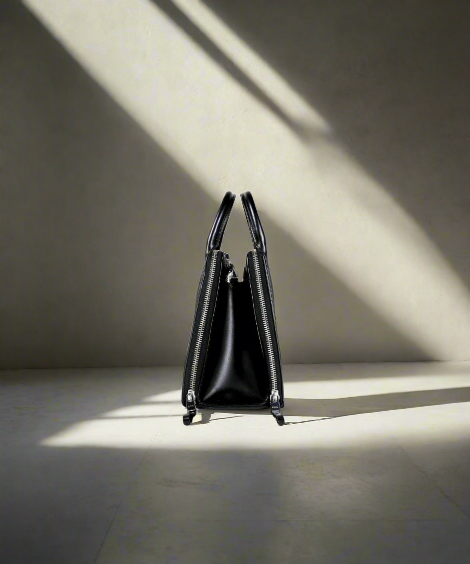 Black leather handbag with a zipper on a white background