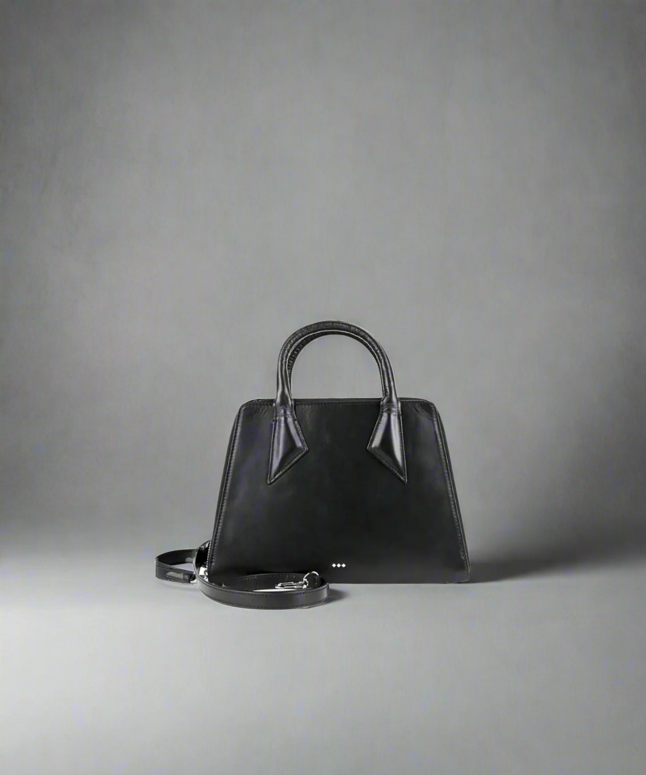 Black handbag with silver accents on a gray background
