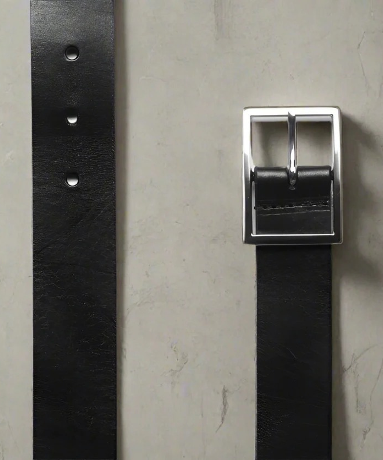 Black Royal RepubliQ leather belt with a silver buckle on a gray background