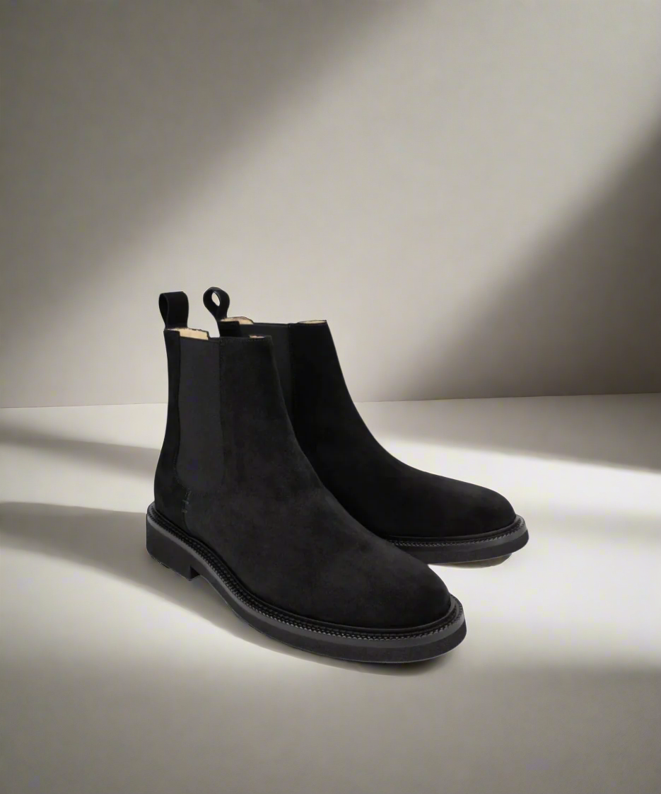 Pair of black Chelsea boots on a light gray background